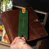 Forest green leather bookmark with silver foil date, heart, and quote displayed on top of a leather planner
